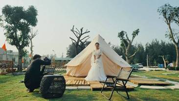 A person in a wedding dress standing in front of a tent

Description automatically generated